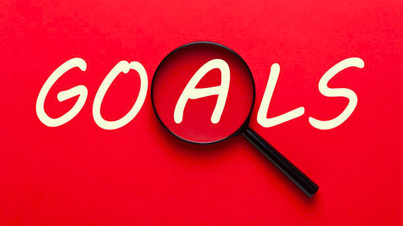 Goals Written On Red Background And Magnifying Glass