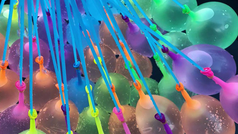 Several multi-colored water balloons squirting water