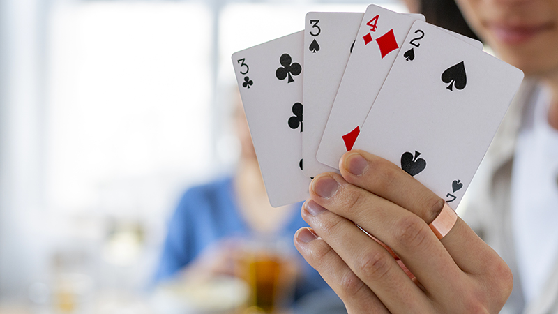 Picture of a hand holding four playing cards.